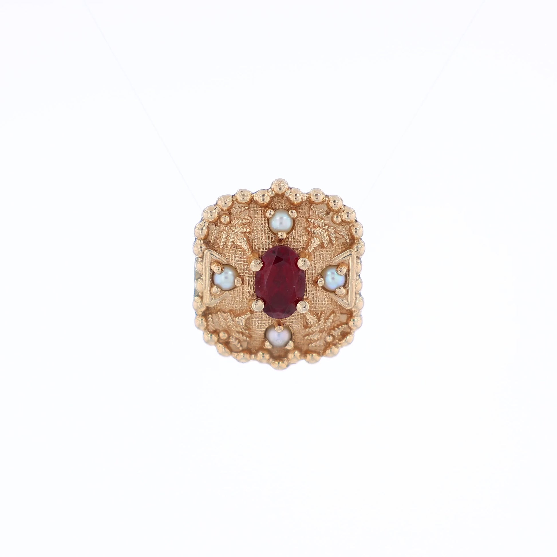 Yellow gold slide pendant with an oval garnet center and surrounding pearls on a white background