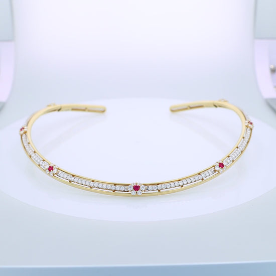 Gold collar necklace with diamond center row and ruby accents on a white background