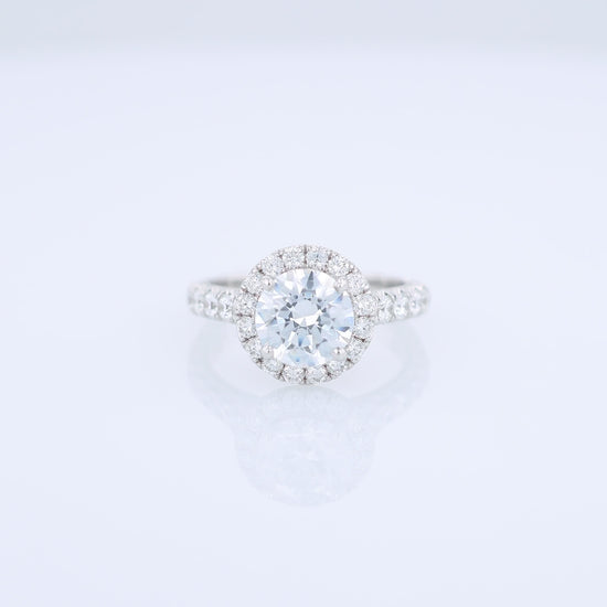 White gold diamond halo engagement ring with diamond accents and a round cubic zirconia center on a white background