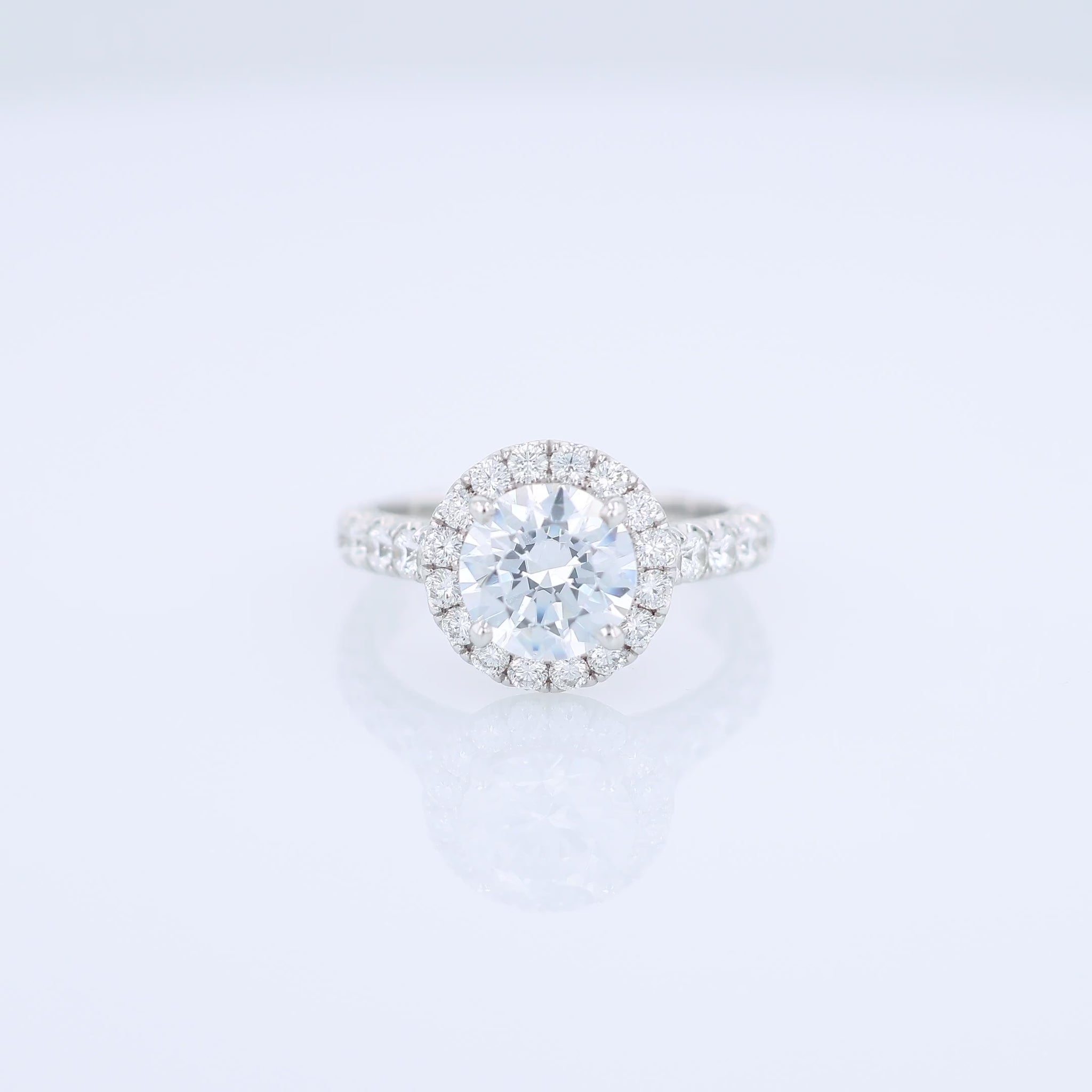 White gold diamond halo engagement ring with diamond accents and a round cubic zirconia center on a white background