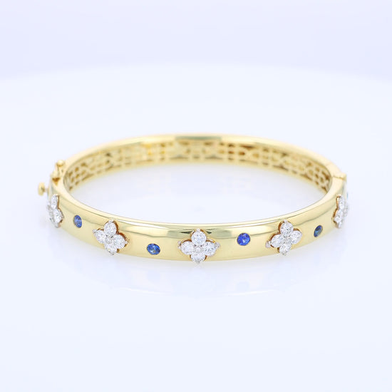 Gold bracelet with diamond and sapphire accents on a white background