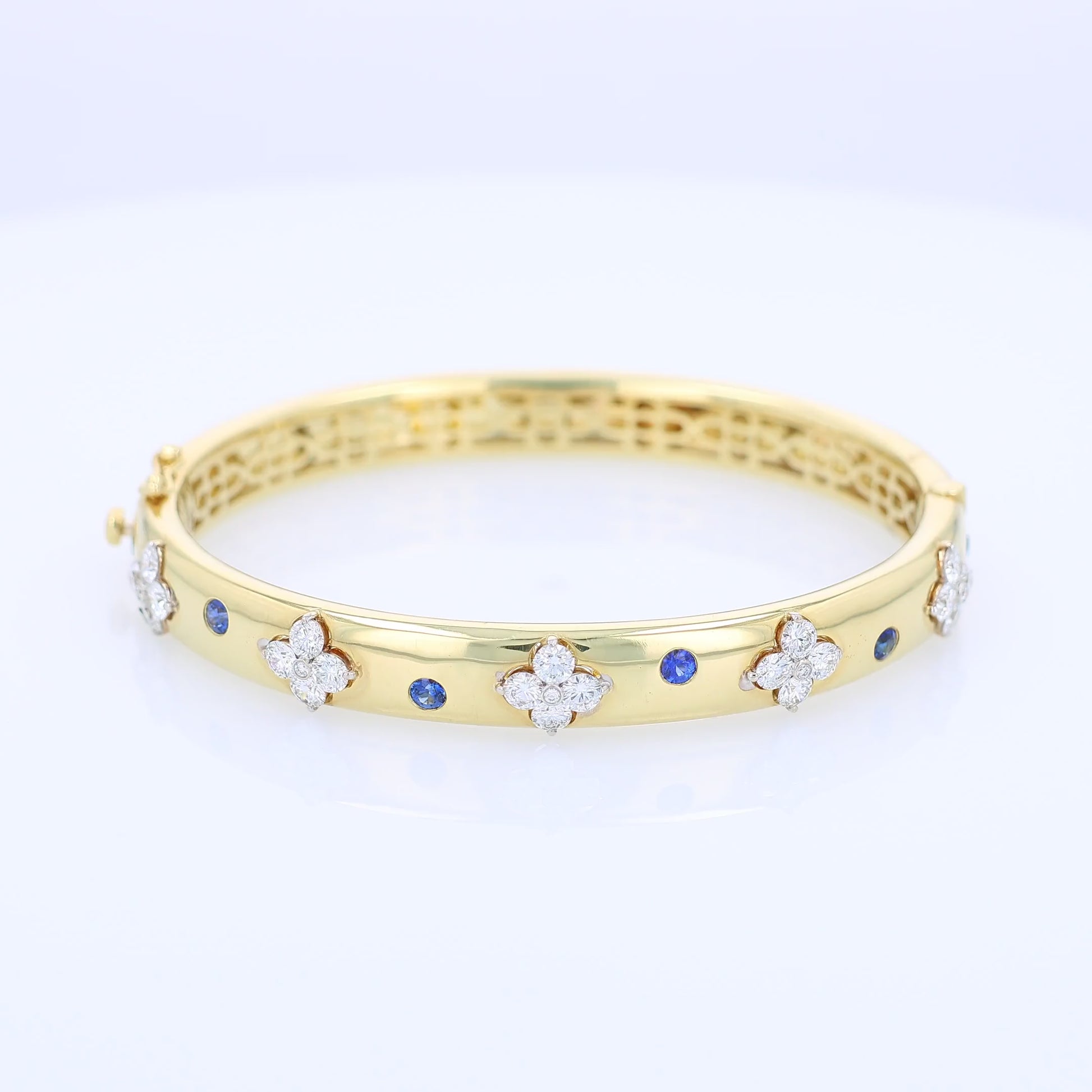 Gold bracelet with diamond and sapphire accents on a white background