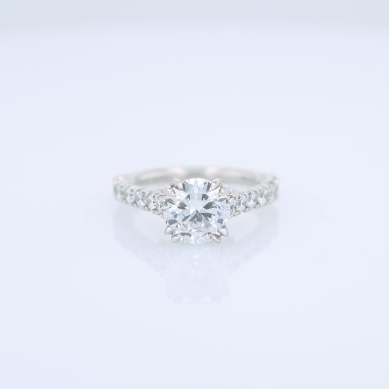 Platinum diamond engagement ring with diamond accents and a round cubic zirconia center on a white background