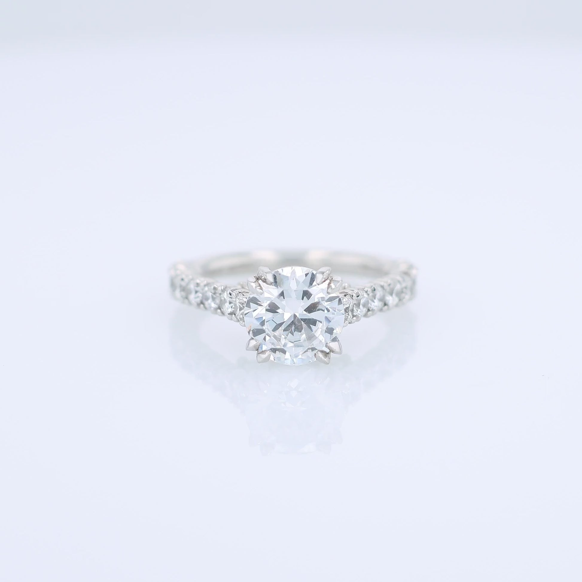 Platinum diamond engagement ring with diamond accents and a round cubic zirconia center on a white background
