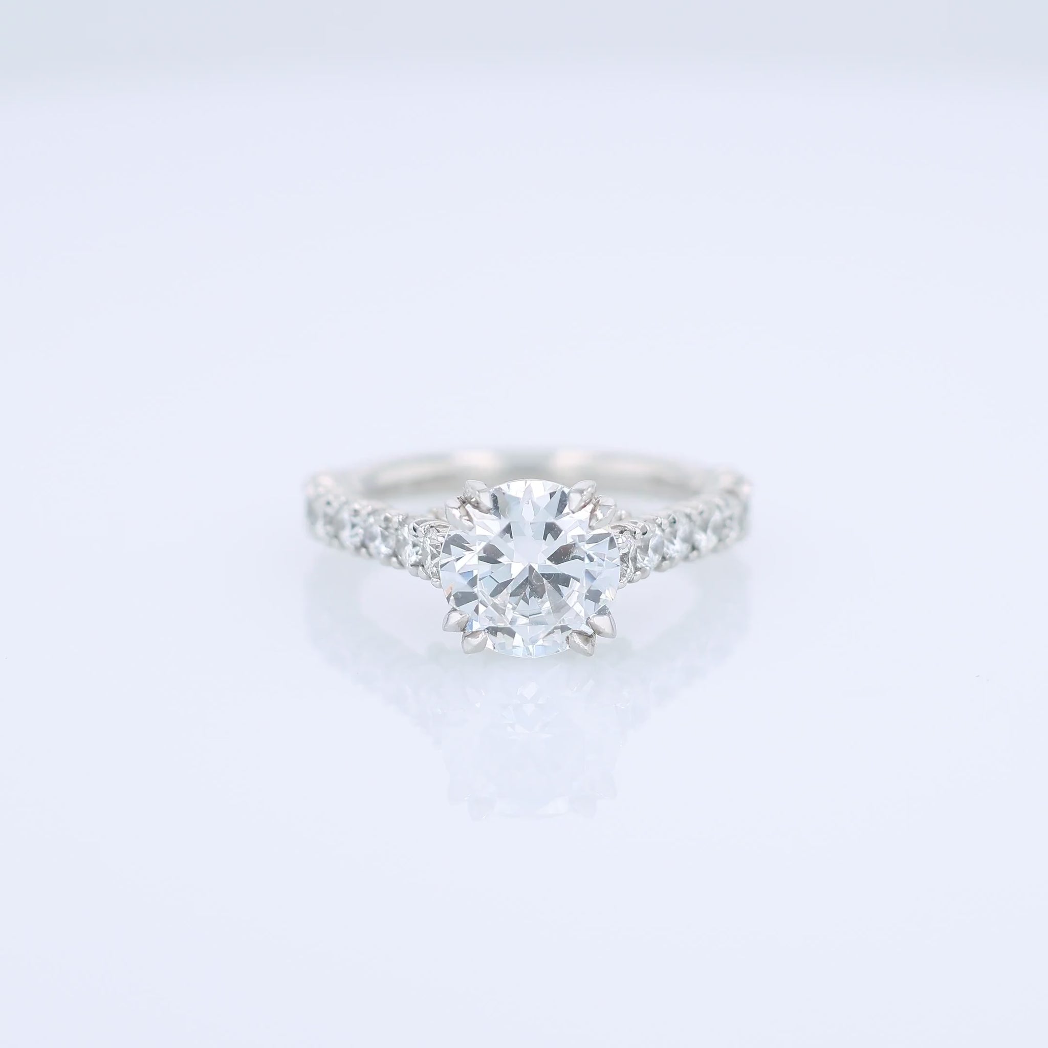 Platinum diamond engagement ring with diamond accents and a round cubic zirconia center on a white background