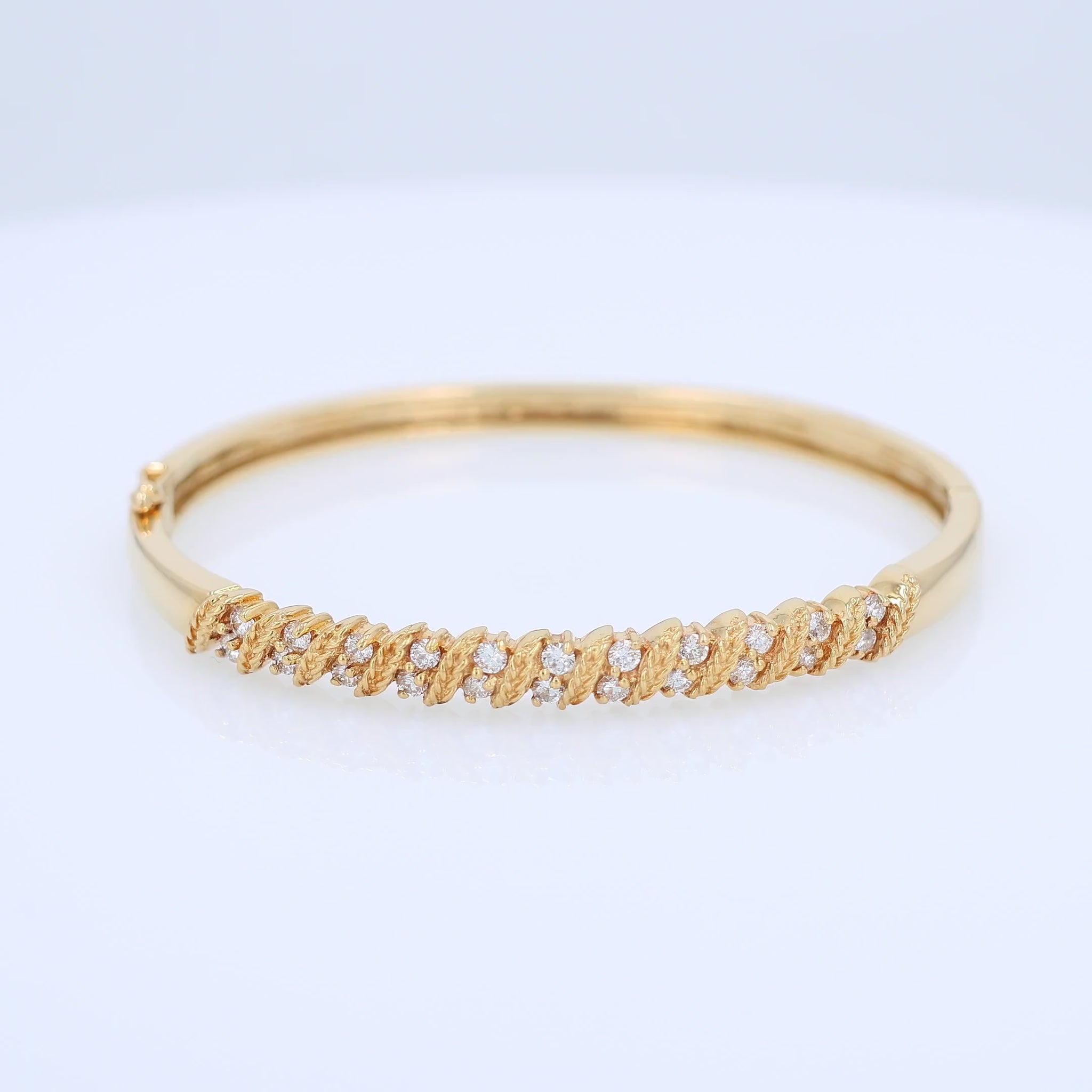Yellow gold rope border diamond bangle bracelet on a white background