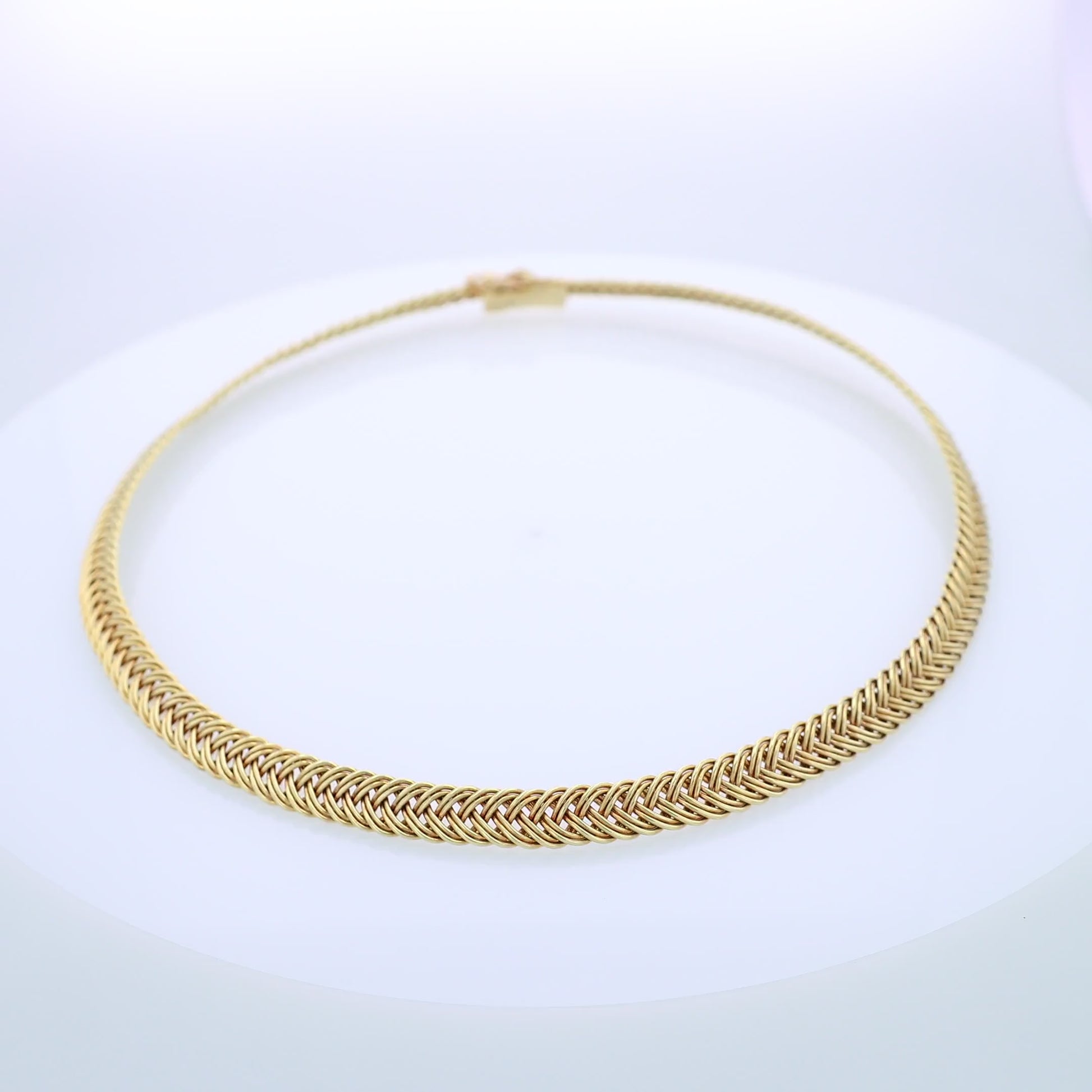 Yellow gold braided collar necklace on a white background