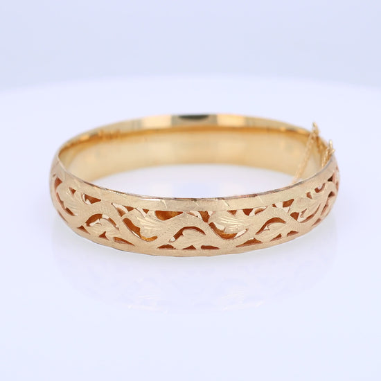 Yellow gold brushed open work design bangle bracelet on a white background
