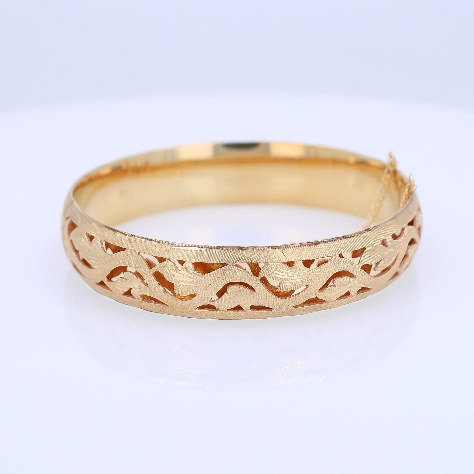 Yellow gold brushed open work design bangle bracelet on a white background