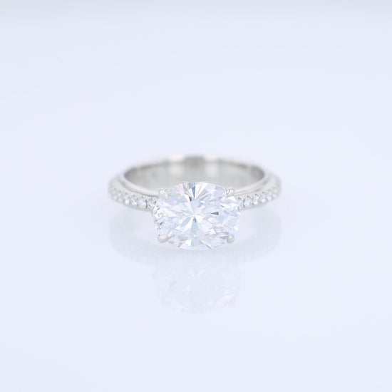 Platinum diamond engagement ring with diamond accents and an oval cubic zirconia center on a white background