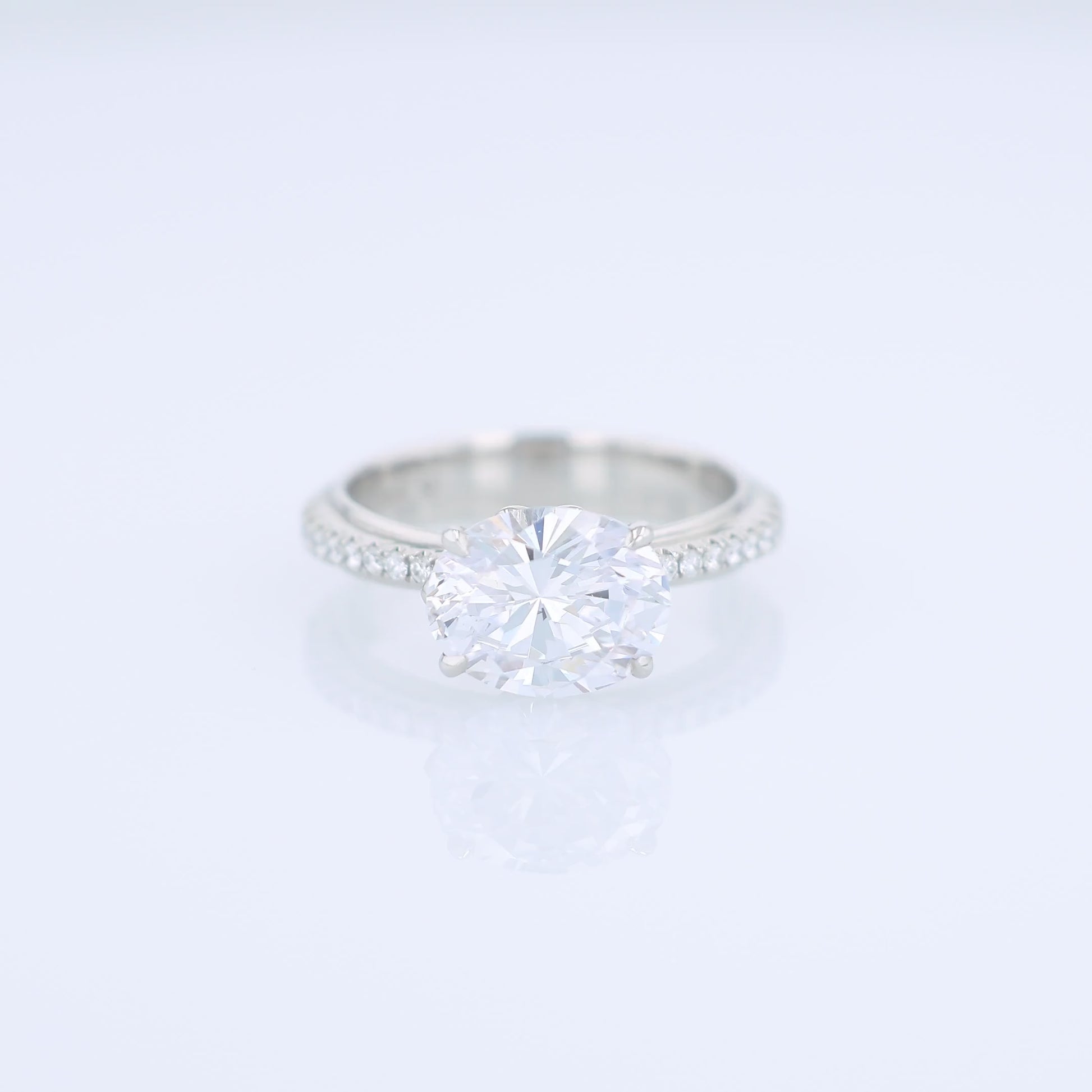 Platinum diamond engagement ring with diamond accents and an oval cubic zirconia center on a white background