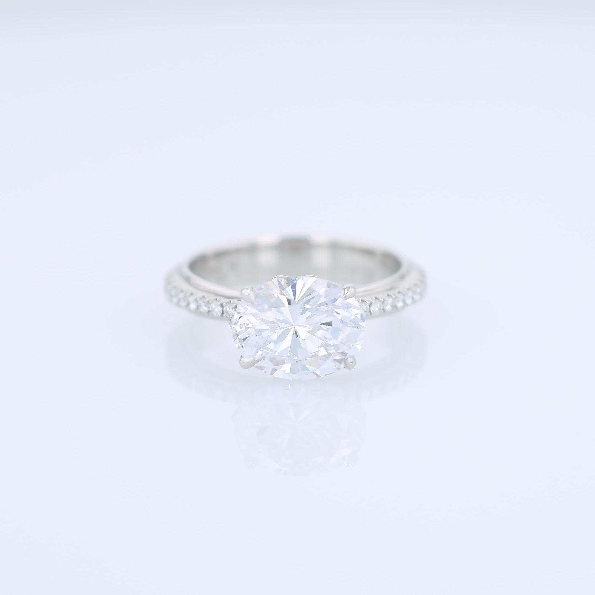 Platinum diamond engagement ring with diamond accents and an oval cubic zirconia center on a white background