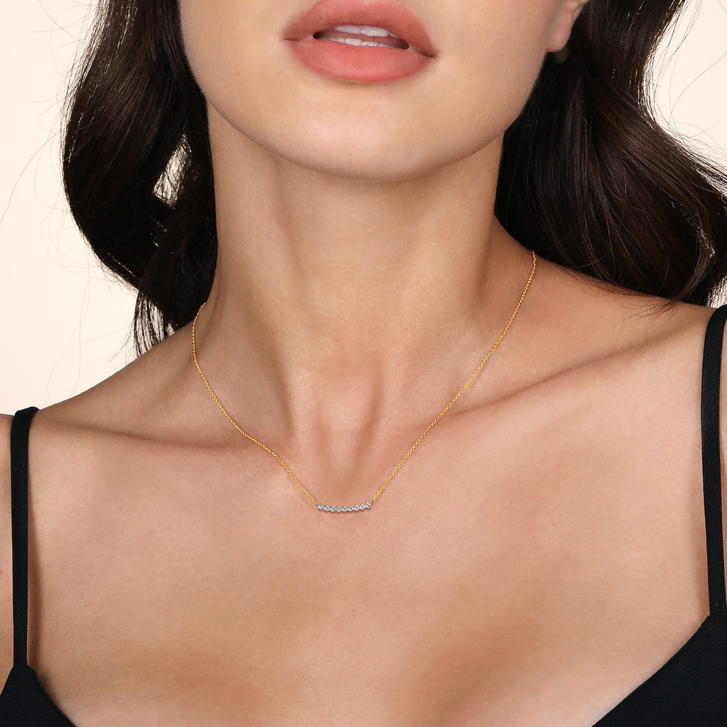 Gold necklace worn by a model with a neutral background