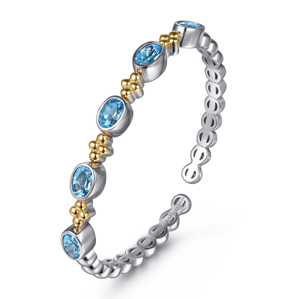 Silver ring with blue gemstones and gold accents on a white background