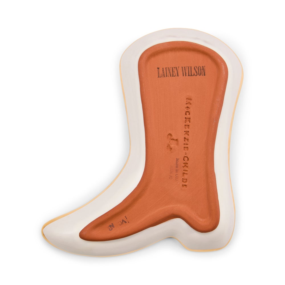 A single foot-shaped insole or shoe insert shown on a plain white background. The insert has a terracotta orange center with embossed text reading 'LAINEY WILSON' and 'MACKENZIE CHILDS', plus a small logo, surrounded by a cream outer edge with a thin tan outline.