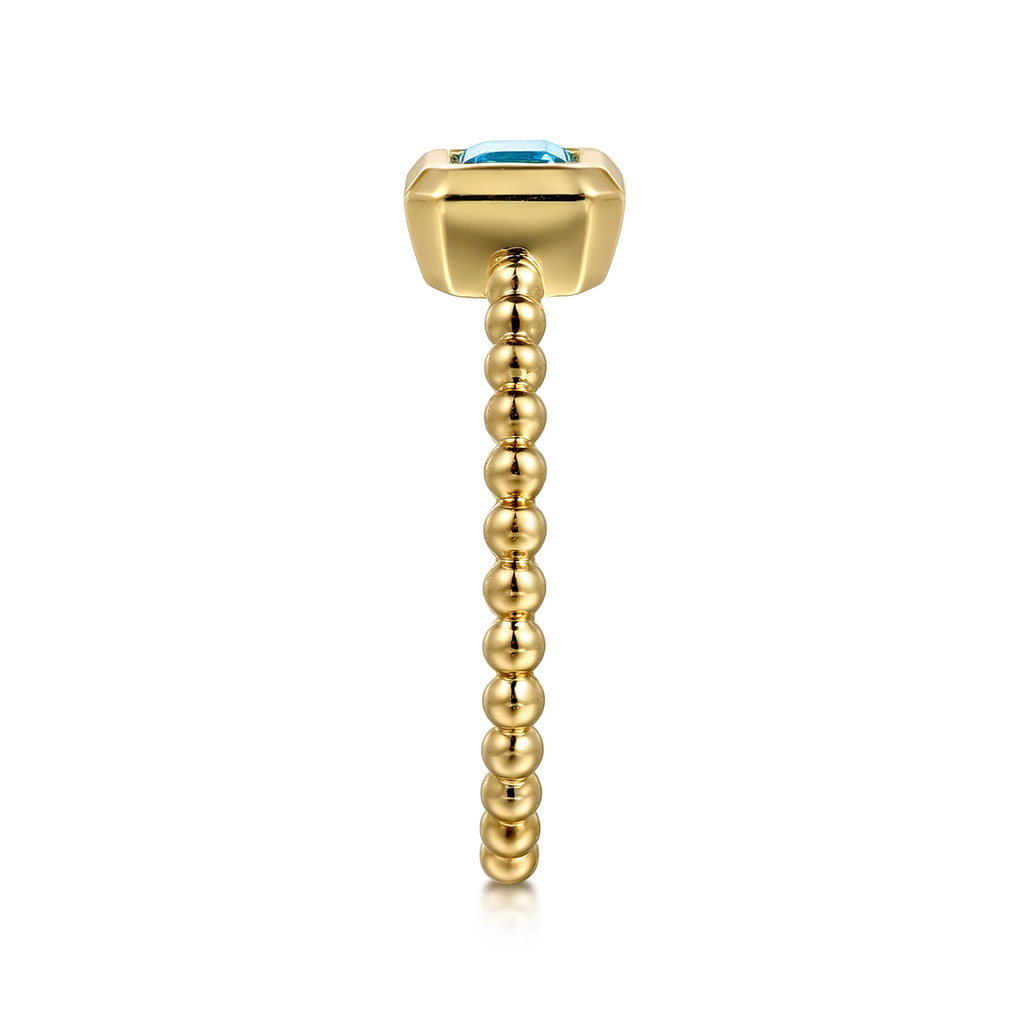 Gold earring with a blue gemstone on a white background