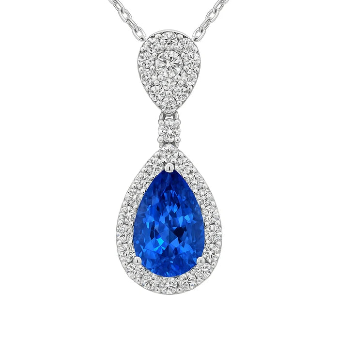 silver tone pendant with blue stone and clear stones on a white background