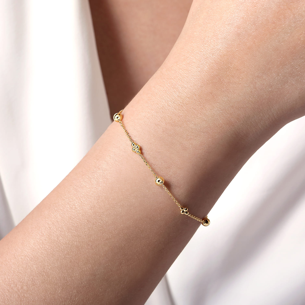 girl wearing gold beaded clover bracelet on natural background