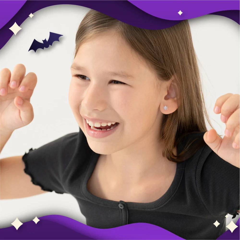 A young girl smiling and posing with a small silver stud earring, framed by purple graphic borders with bat illustrations.