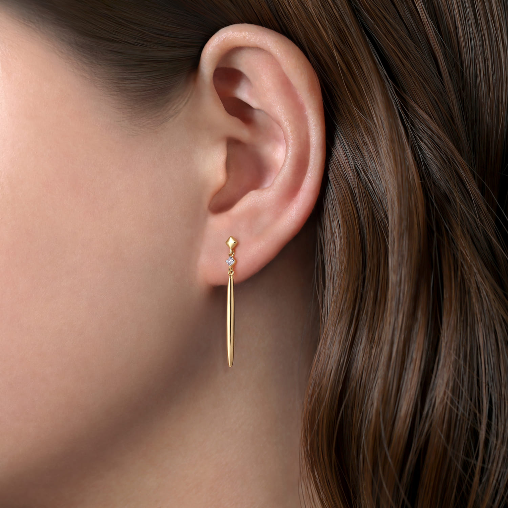Gold earring worn by a person with brown hair