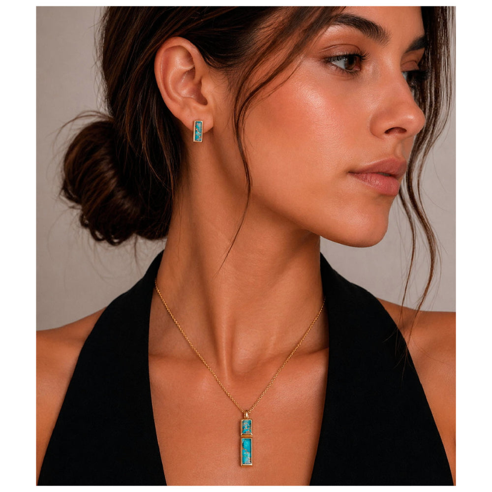 A woman in a black halter top models a gold necklace and matching stud earring, both featuring a vertical rectangular turquoise-blue stone in a gold bezel setting, against a neutral gray background.