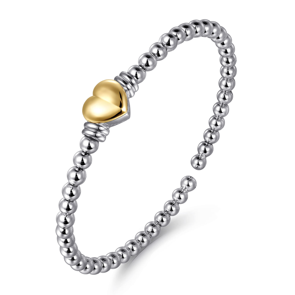Silver beaded ring with a gold heart-shaped charm on a white background