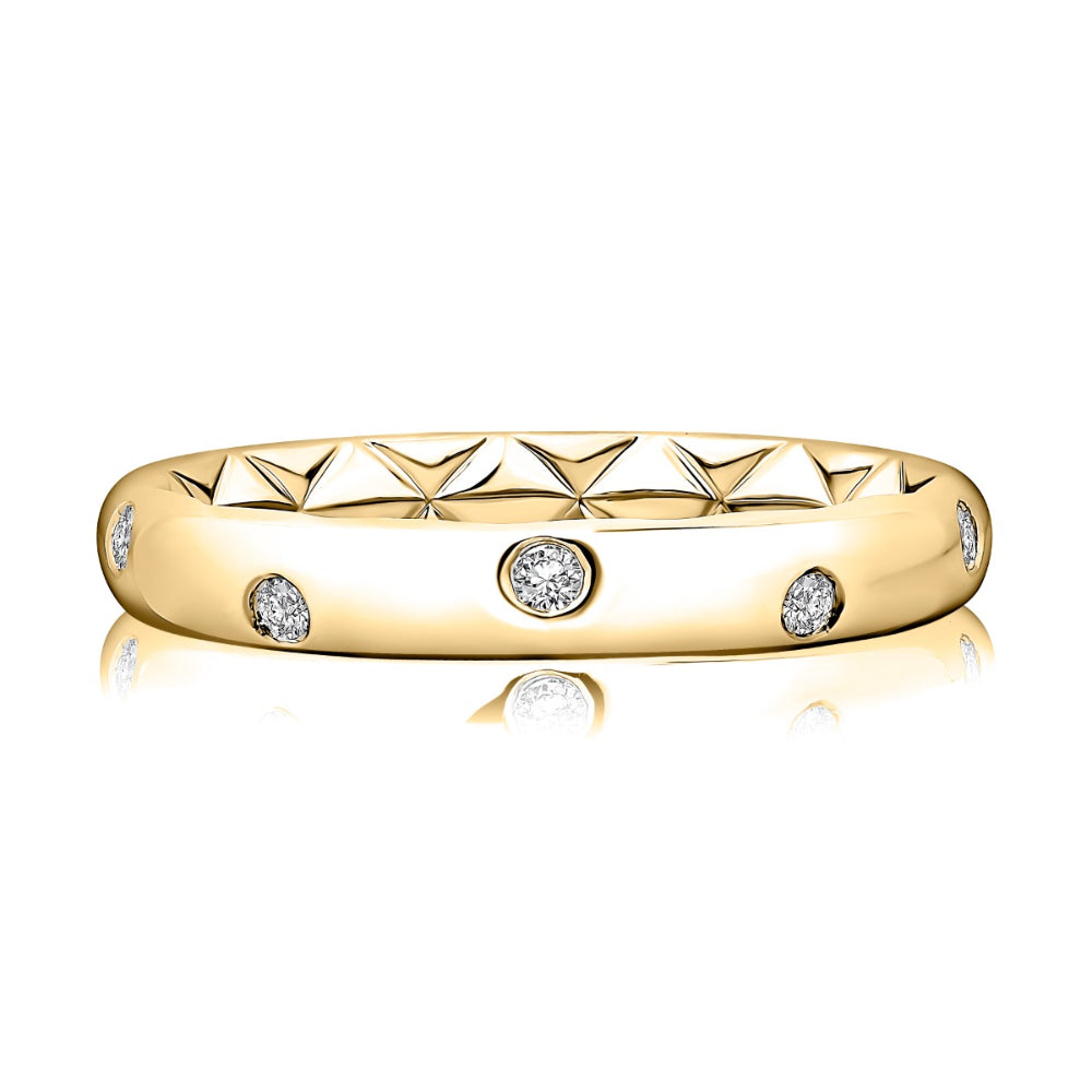 A yellow gold eternity-style ring with a textured geometric pattern on the band and three round-cut clear gemstones, shown on a white background with a soft reflection.