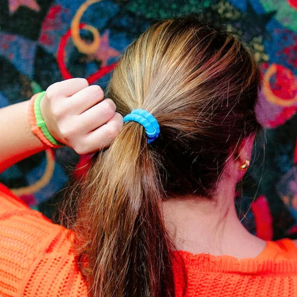 Person with a blue hair tie in their ponytail against a colorful background