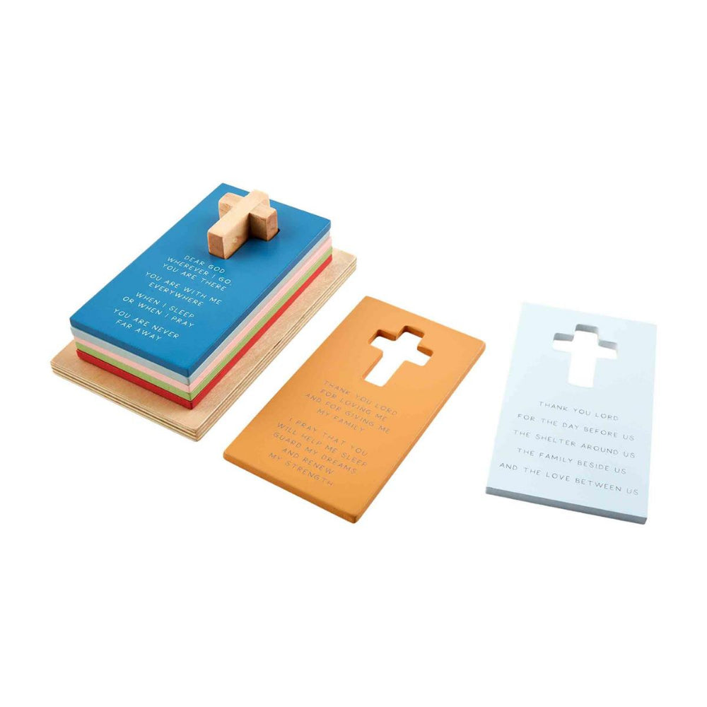 A colorful wooden puzzle set designed to stack on a cross post, featuring pieces with prayers printed on them on a white backround.