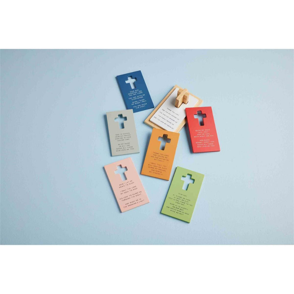 A colorful wooden puzzle set designed to stack on a cross post, featuring pieces with prayers printed on them on a blue backround.
