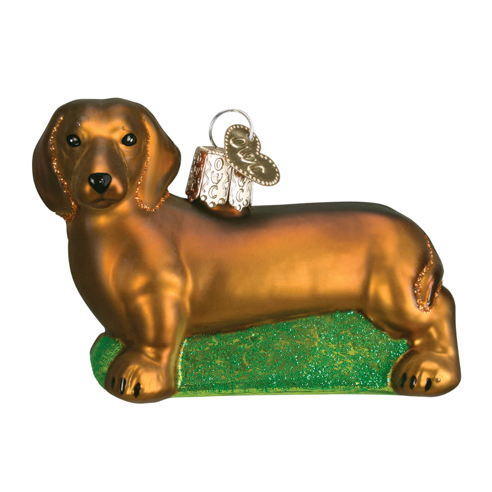 A christmas ornament of a brown Dachshund on a white backround. 