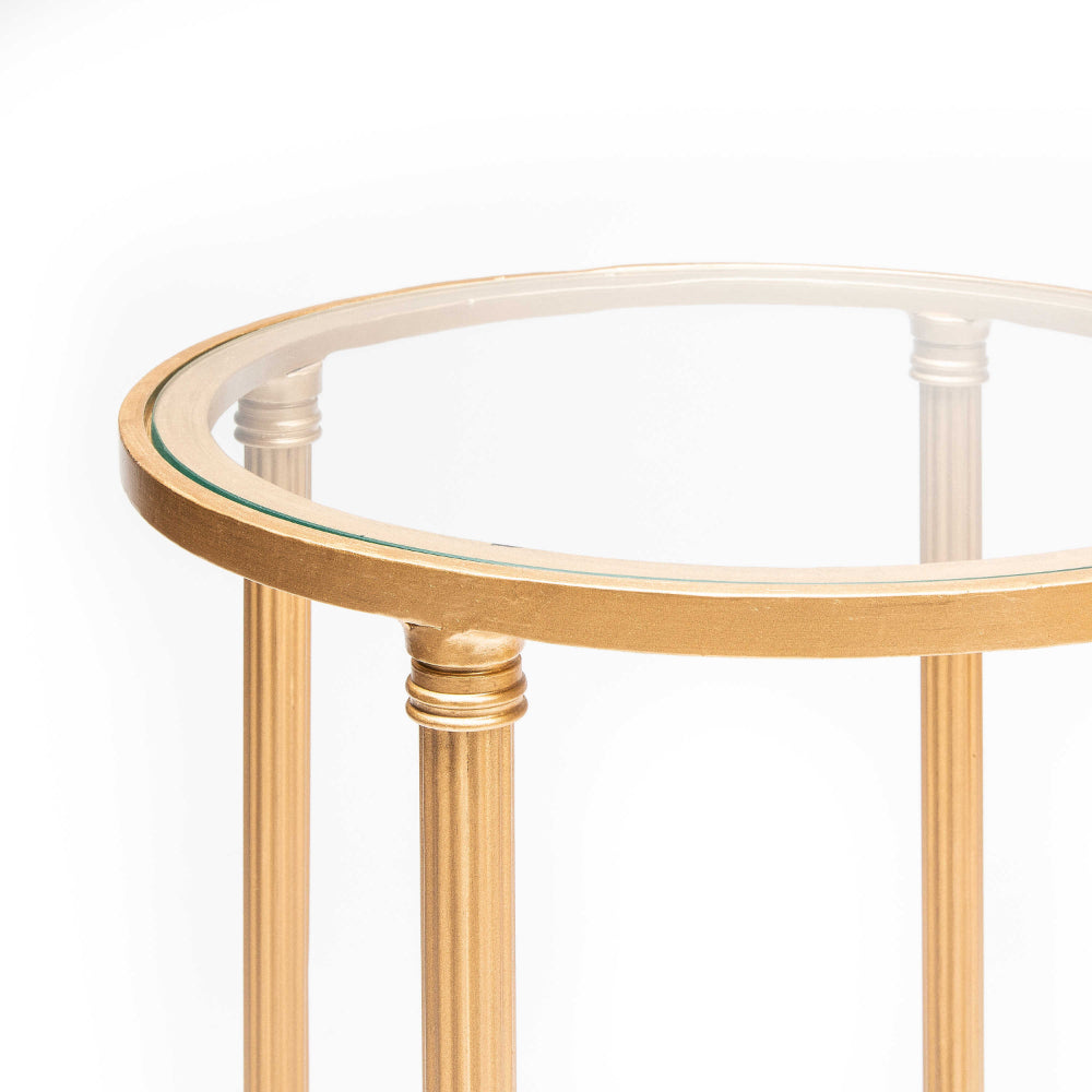 A close up photo of the top of a gold-framed glass side table with a decorative white and black lower shelf on a white background