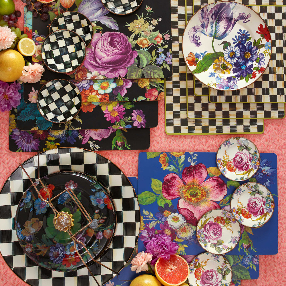 Set of four black and white checkered placemats and other courtly check and Mackenzie-Childs items on a pink table clothed table