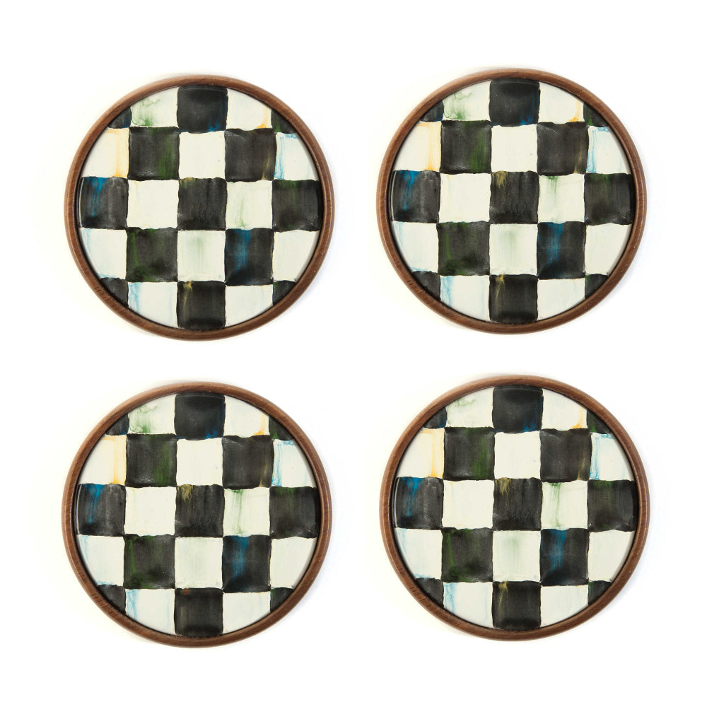 Four round black & white checkered coasters with a dark brown wooden border on a white background