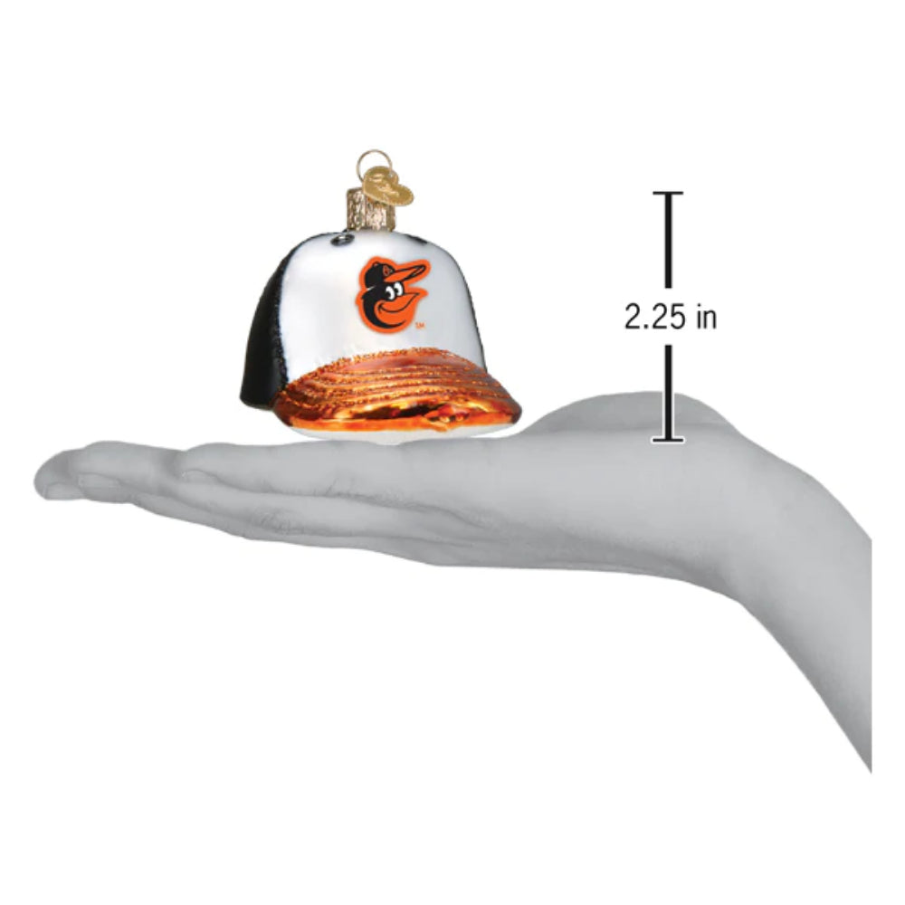 Glass ball cap ornament with a Orioles logo with measurements on a hand on a white background.
