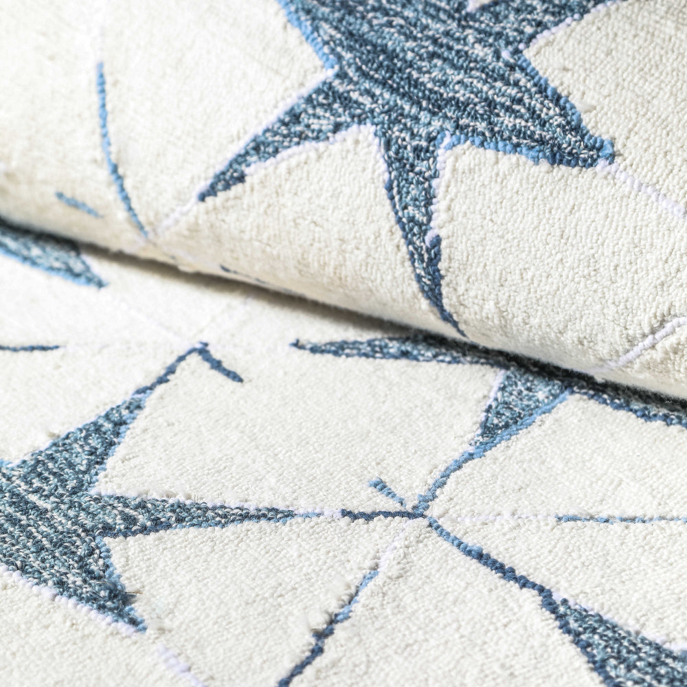 A close up photo of a rectangular indoor/outdoor rug with a pattern of blue stars on it. 