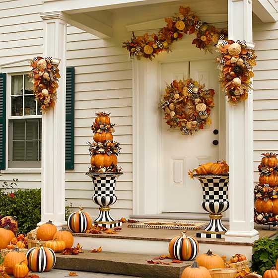 Life style photo of MacKenzie-Childs Courtly Check Pedestal Urn on a front porch with other fall decor and pumpkins