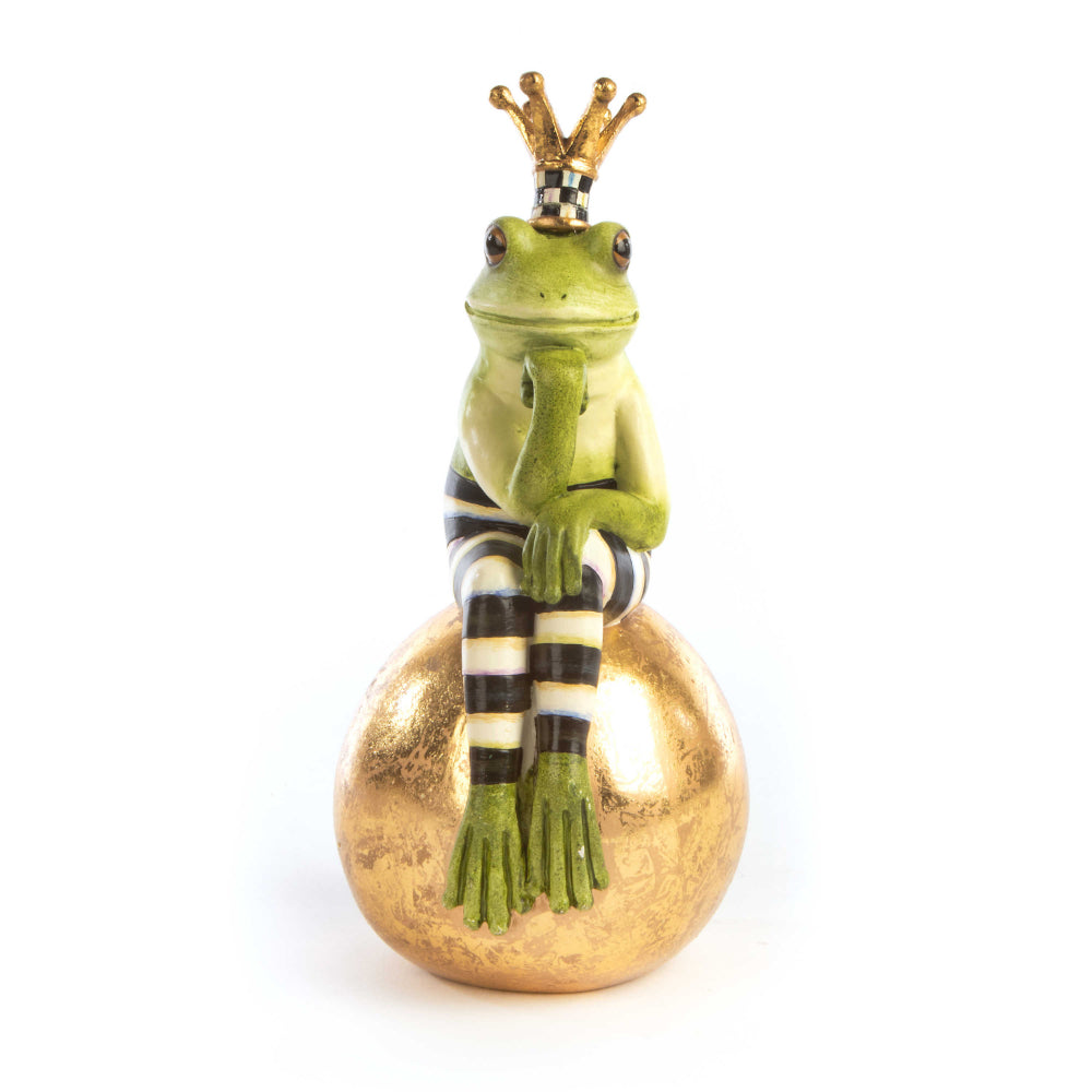 A hand-painted green frog with black and white stripes, sitting on a gold-leafed ball, wearing a crown.