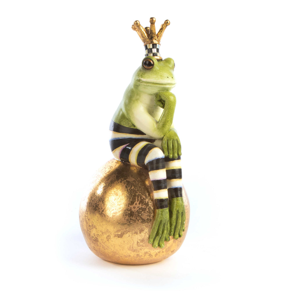 A hand-painted green frog with black and white stripes, sitting on a gold-leafed ball, wearing a crown.