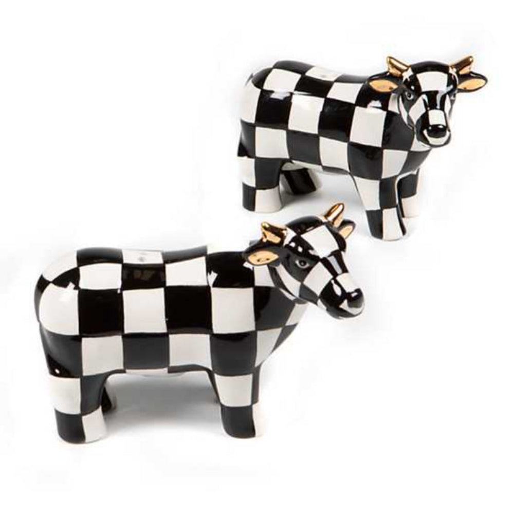 A pair of hand-painted ceramic cows with in a black checkered pattern and gold luster ears designed to hold salt and pepper on a white backround 