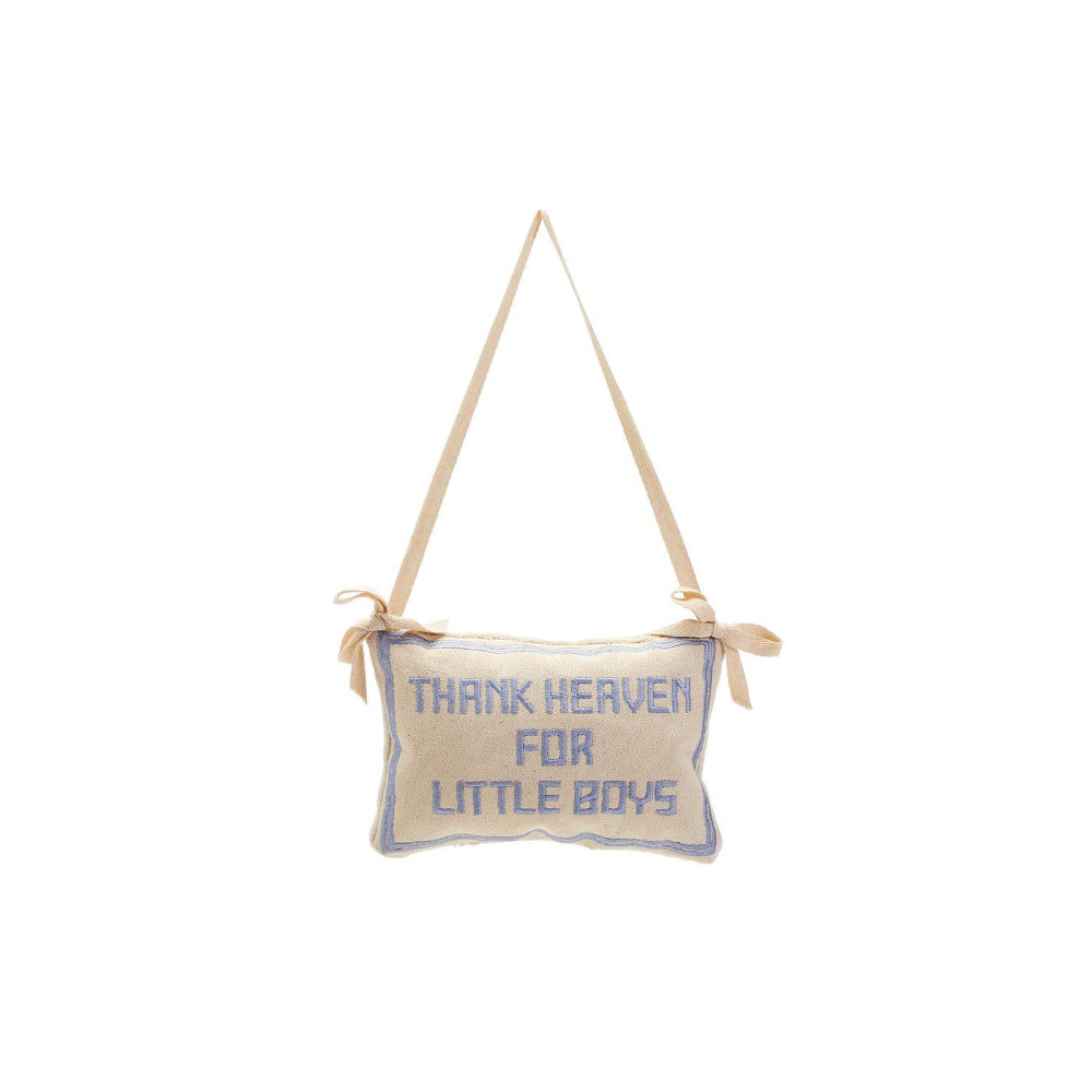 A beige embroidered pillow with the phrase 'Thank Heaven for Little Boys' in blue on a white background.