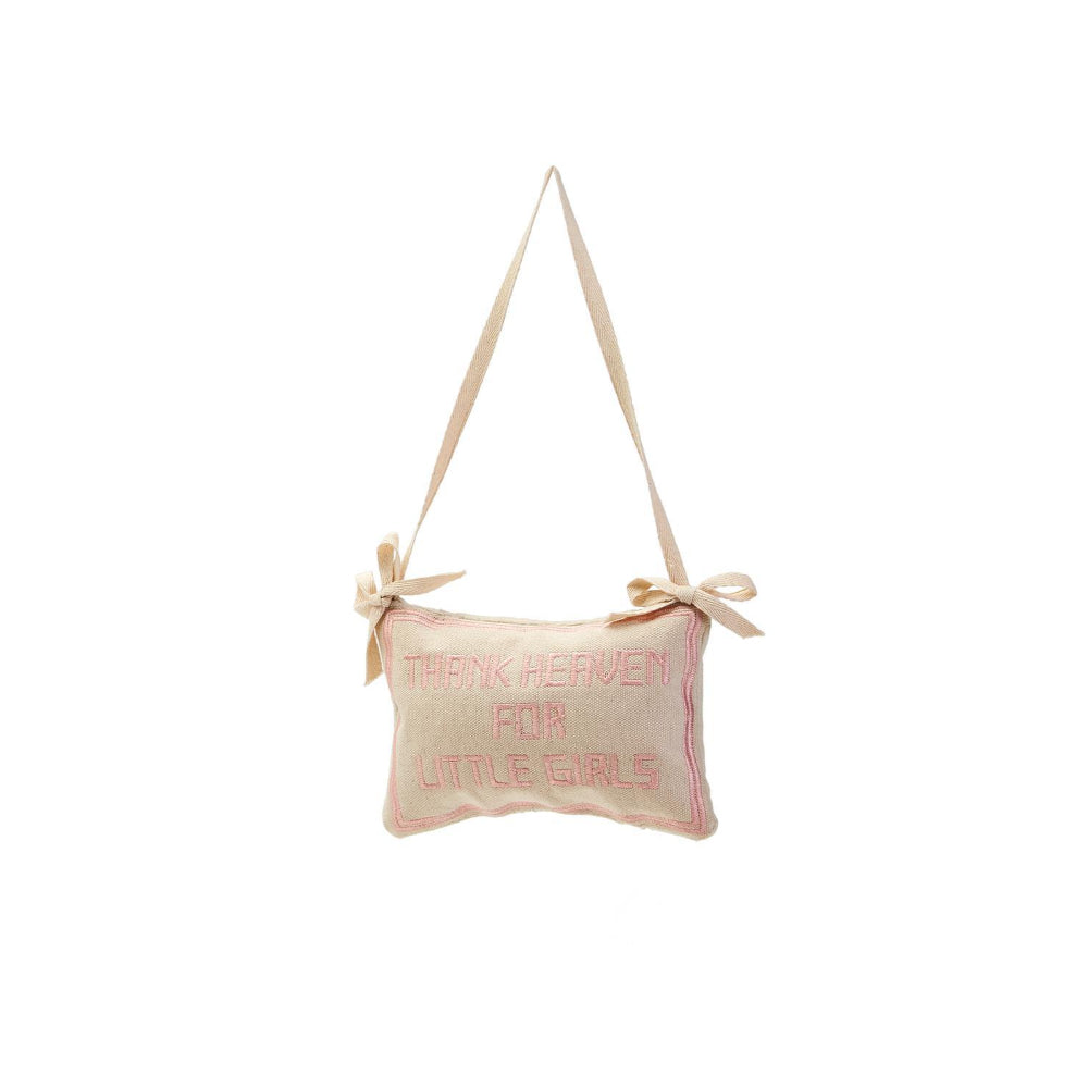A beige embroidered pillow with the phrase'Thank Heaven for Little Girls', in  pink  on a white background.