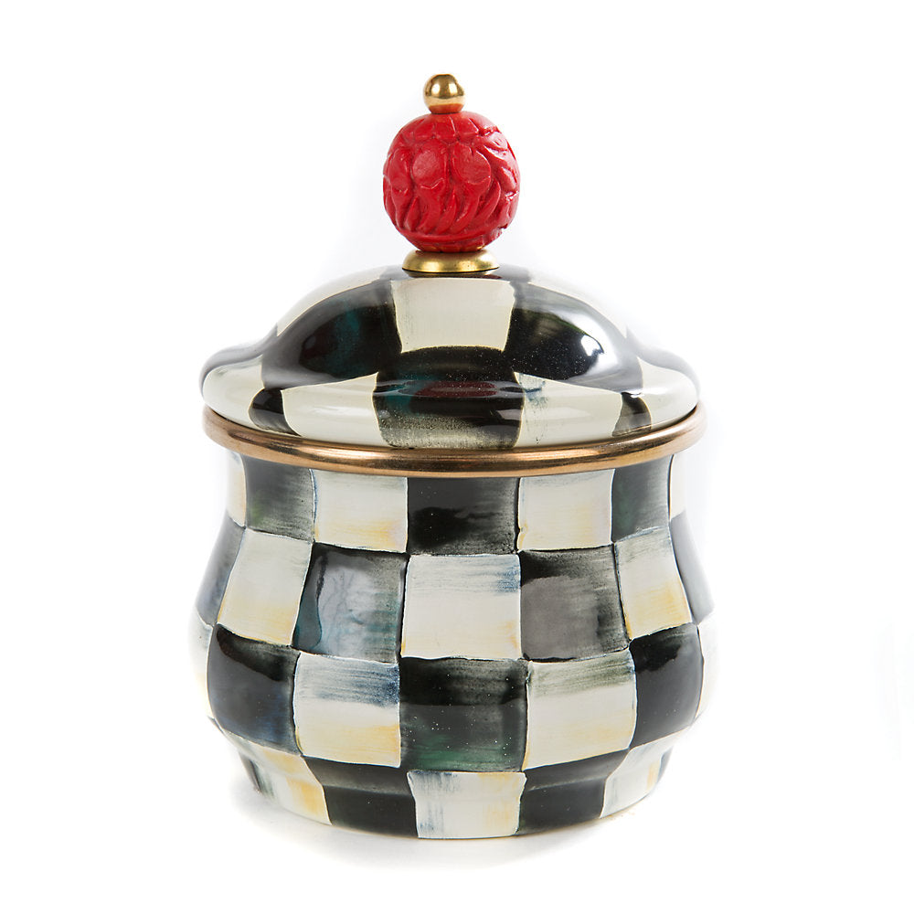 A lidded sugar bowl with a Courtly Check enamel pattern and a red faux-cinnabar bead on the lid handle, rimmed in bronzed stainless steel.