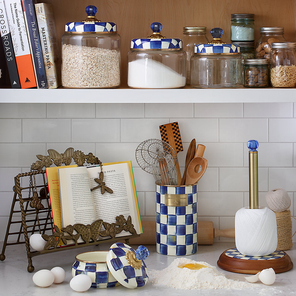 Life Style photo of a  decorative jar with royal blue and white checkered pattern with a kitchen background.