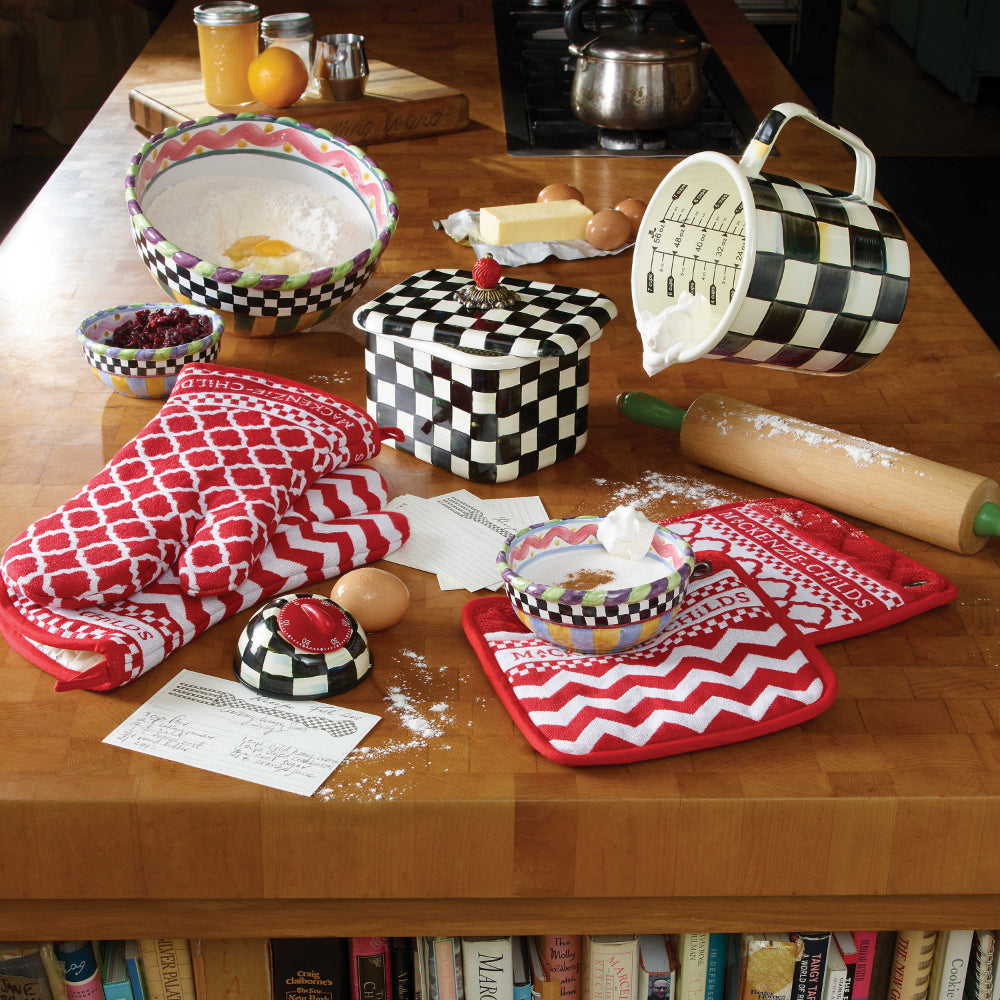 Measuring cup with black and white checkered pattern on a wood table with other cookware making cookies 