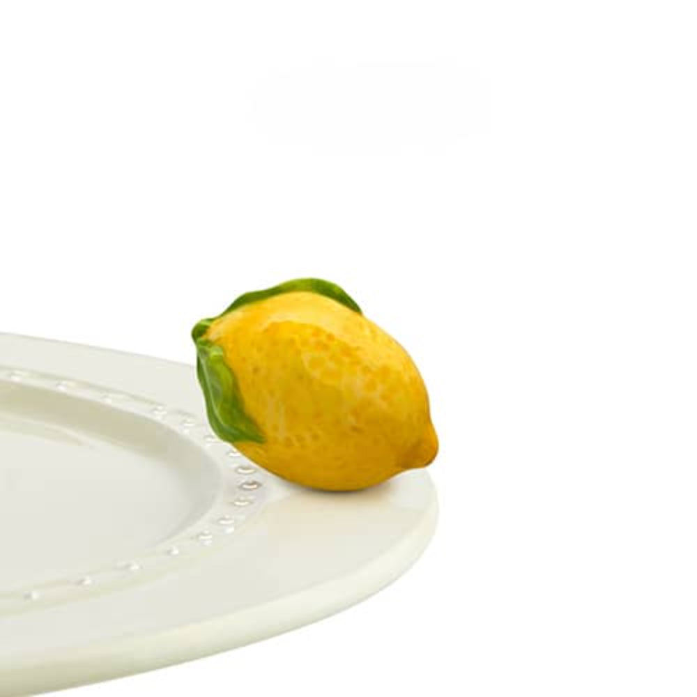 Yellow lemon mini with green stem on a white plate