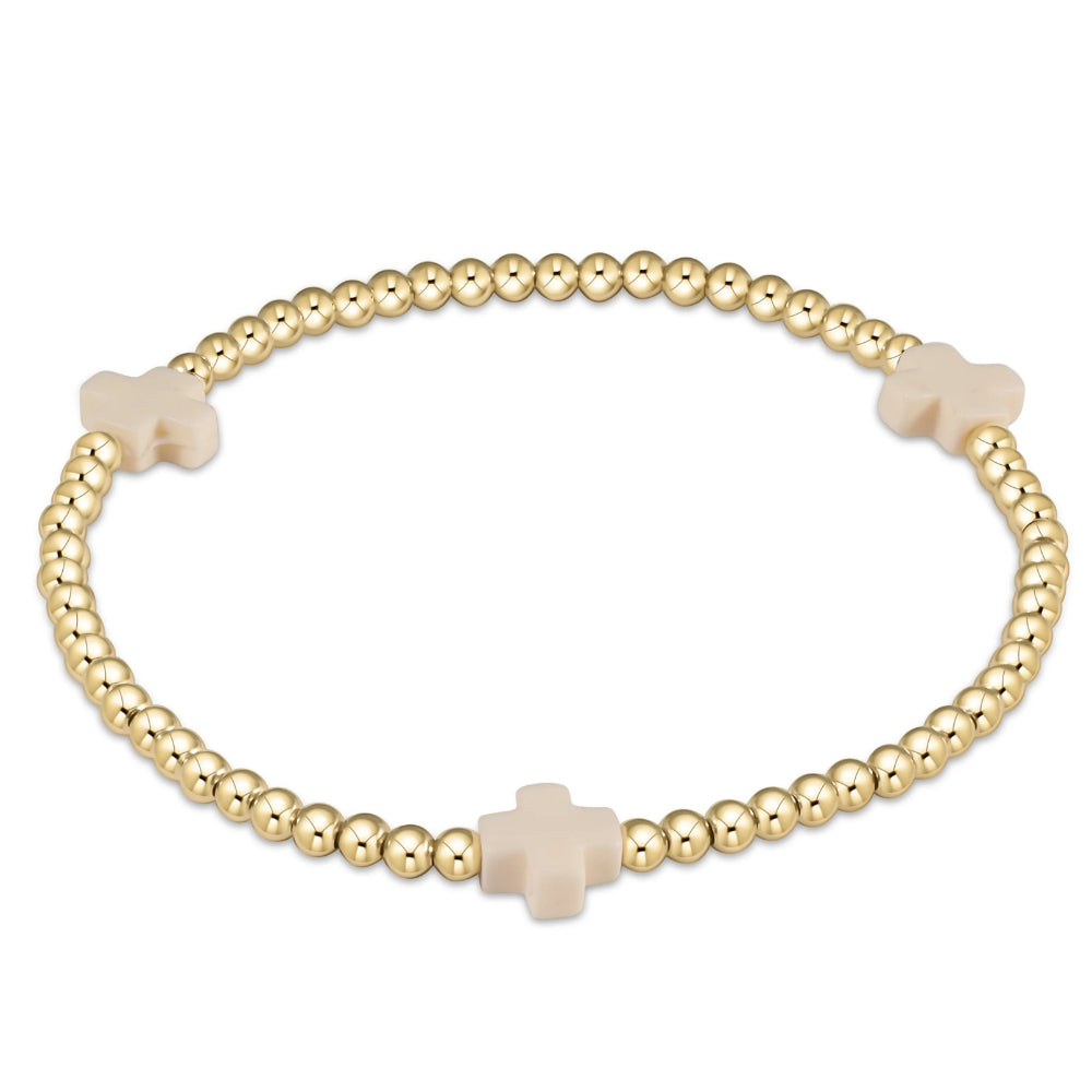 Gold beaded bracelet with beige cross charms on a white background