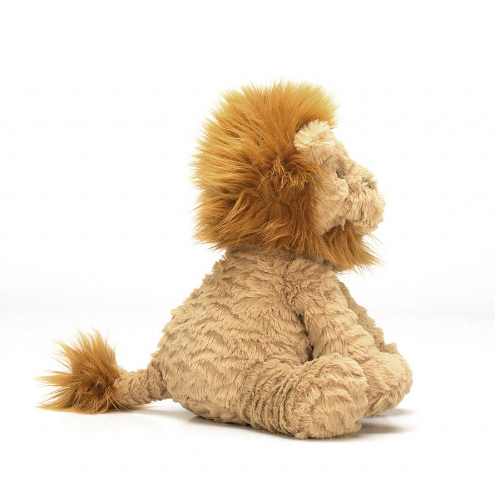 A side photo of a medium-sized plush toy lion with beige fur and an amber mane, sitting upright on a white backround 