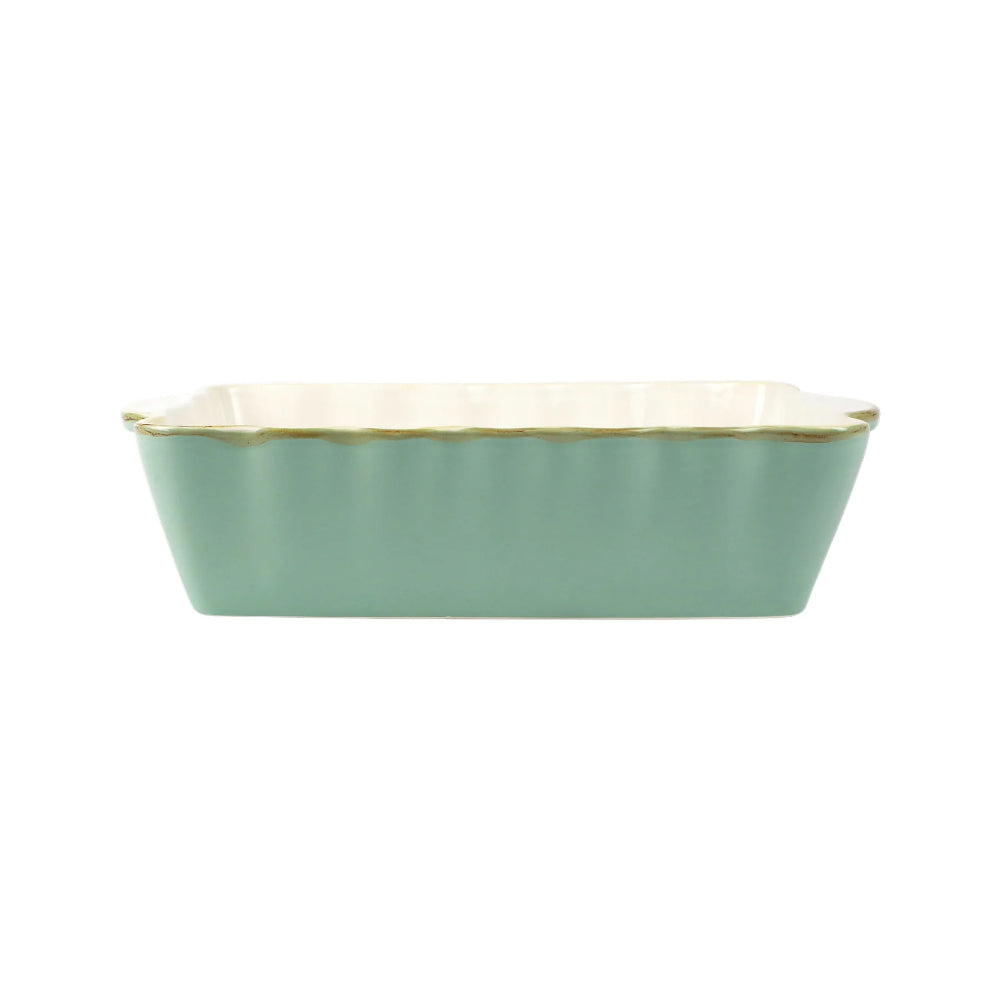A medium rectangular stoneware baker with scalloped edges and gold rim with  a bright aqua color with a beige interior.