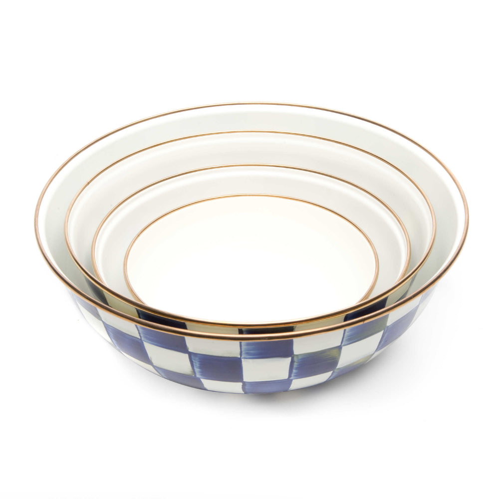 four sizes of a hand-painted steel bowl with a royal check enamel pattern with a white interiors and a bronzed stainless steel rim on a white backround 
